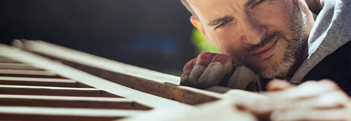 Person baut ein Gartenhaus aus Holz